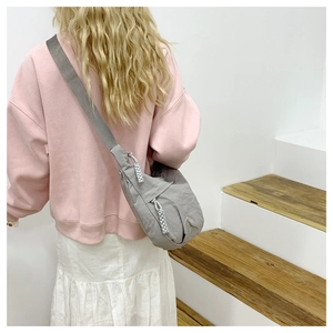 Detail of grey half-moon crossbody bag in wrinkled fabric with textured strap