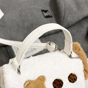 Detailansicht der weißen Plüschtasche mit Ledergriff und brauner Bärenstickerei darauf