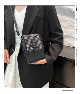 Détail du sac bandoulière en cuir noir avec strass argentés et boucle en anneau D
