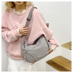 Detail of grey nylon crescent bag with adjustable wide shoulder strap and woven zipper pull