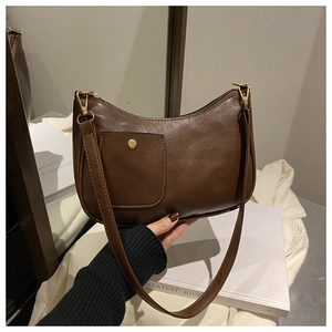 Detail of dark brown faux leather crescent bag with golden buckle and sleek texture