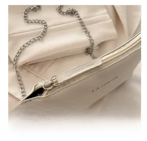 Close-up of smooth zipper detail and lychee texture on white minimalist crossbody bag