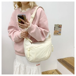 Detail of white nylon crescent crossbody bag featuring soft pleated texture and adjustable strap