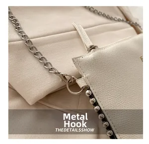 Close-up of white pebble leather bag featuring silver chain and metal rivet hardware detail