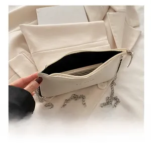 Detail view of white envelope bag showing spacious interior for smartphone and silver chain