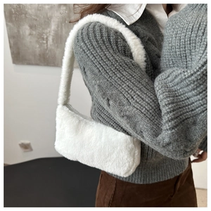 Detail of white faux fur shoulder bag texture shown on a grey sweater and brown pants