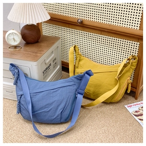 Detail of blue and yellow nylon crescent crossbody bags with woven zipper pullers