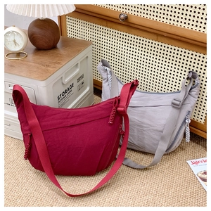 Detail of burgundy and light gray nylon crescent bags with texture and knotted zippers