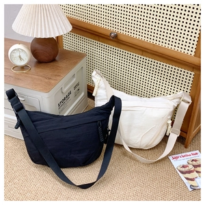 Detail of half-moon crossbody bags in black and cream beige with adjustable straps