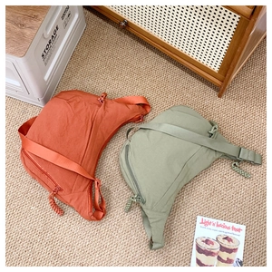Detail of crescent crossbody bags in brick red and olive green with nylon texture