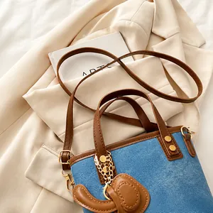Détail du sac seau en denim avec garniture en cuir marron et boucles dorées