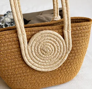 Detail of woven straw tote bag featuring spiral handle attachment and gold thread texture