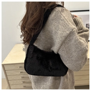 Close-up of fluffy black plush shoulder bag styled with a minimalist knit sweater