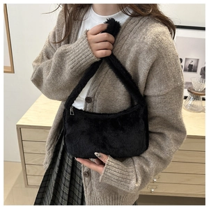Gros plan du sac bandoulière en fausse fourrure noire avec texture pelucheuse et zip