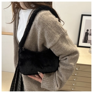 Detail of black faux fur baguette bag with soft plush texture and silver metal zipper