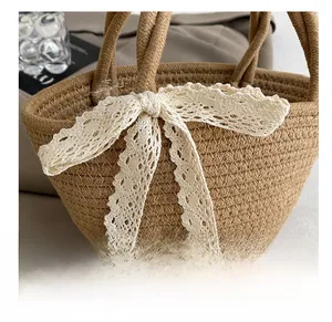 Gros plan sur la texture du sac en paille tressée avec nœud délicat en dentelle blanche