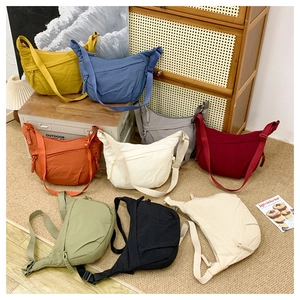 Nine colorful nylon crescent crossbody bags displayed together in various stylish hues