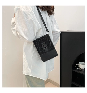 Détail du sac à bandoulière noir avec strass et boucle en D porté par le mannequin