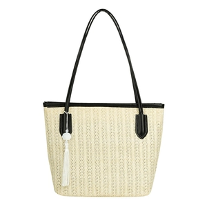 Large beige straw tote bag with black straps and white floral tassel charm