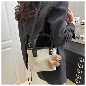 Vue détaillée du sac seau vert-gris avec bordure en cuir et pendentif chien créatif