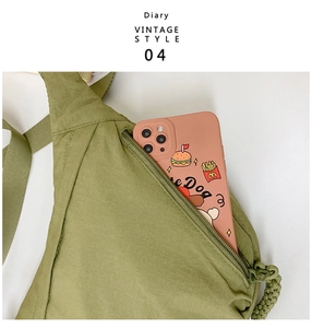 Detail of moss green nylon crossbody bag with woven zipper pull and front pocket storage