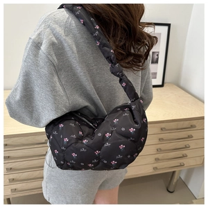 Detalle de bolso acolchado floral con nudo decorativo en la correa usado por una modelo