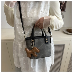 Détail du sac seau gris avec breloque chiot marron et logo gaufré tendance
