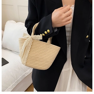 Detailed close-up of beige straw tote bag with elegant lace bow detail and woven texture