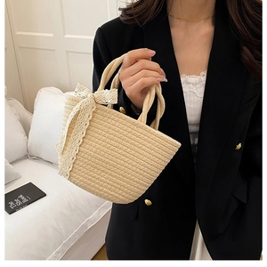Detail of beige straw tote bag with elegant white lace bow and woven rope texture