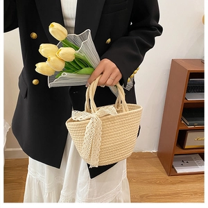 Détail du sac à main en paille tissé avec nœud en dentelle blanche et design élégant