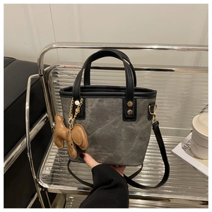 Detail einer grauen Mini-Tragetasche mit goldenen Beschlägen und Hundeanhänger im Regal