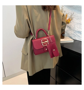 Detail of burgundy lychee leather handbag set with gold buckle on a khaki blazer