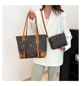 Close-up of brown monogram tote bag set with matching zipper pouch and charm on a model