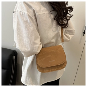 Sac à bandoulière marron plissé avec logo blanc porté par un mannequin en studio