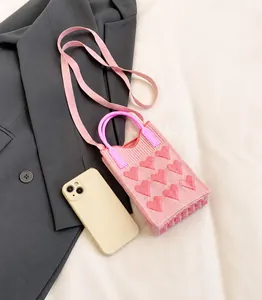 Pink heart-patterned knitted mini bag size comparison with a smartphone side by side