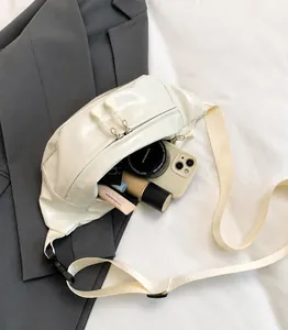 Detail view of large capacity white glossy sling bag with dual zippers and woven strap