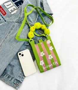 Detalle de bolso de punto para móvil con rayas verdes y rosas y patrones de flores blancas