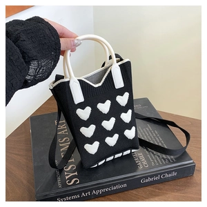 Detailed knit texture of a black and white handbag with heart pattern on books