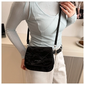 Détail d'un sac besace noir texturé avec typographie mode et finitions métalliques