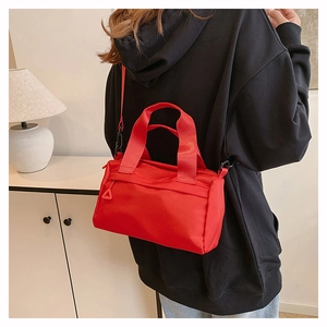 Vista lateral de un bolso bandolera de nailon rojo combinado con una sudadera con capucha