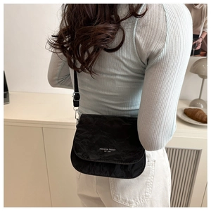 Détail du sac à bandoulière plissé noir avec lettrage fashion et accessoires en argent