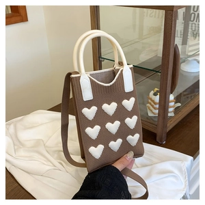 Close-up of heart pattern knit bag with soft texture and white cylindrical handles