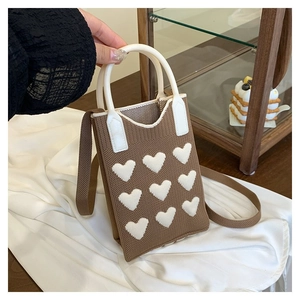 Detailed view of brown knitted mini bag featuring white hearts and leather-reinforced handles