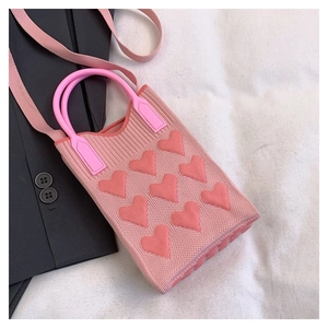 Detalle del bolso de punto rosa con patrones de corazones 3D y asas de resina