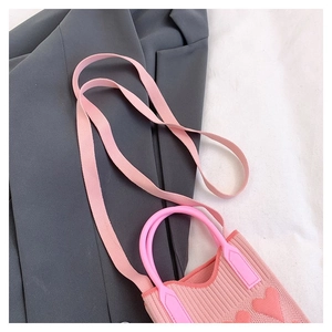 Primer plano de minibolso de punto rosa con corazón sobre blazer gris y fondo blanco