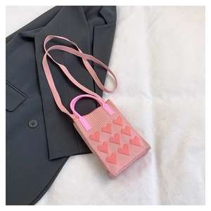 Detalle de mini bolso de punto rosa con patrón jacquard de corazones y asa redonda