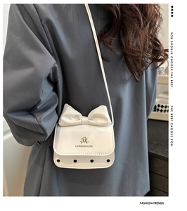 Gros plan du mini sac blanc avec un grand nœud et des détails à pois noirs