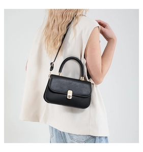 Close-up of matte black leather bag featuring a gold rectangular twist lock and handle