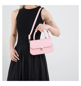Close-up of pink leather handbag with gold metal lock and adjustable shoulder strap