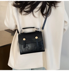 Close-up of black retro bag featuring golden rivets and star embossed pattern detailing